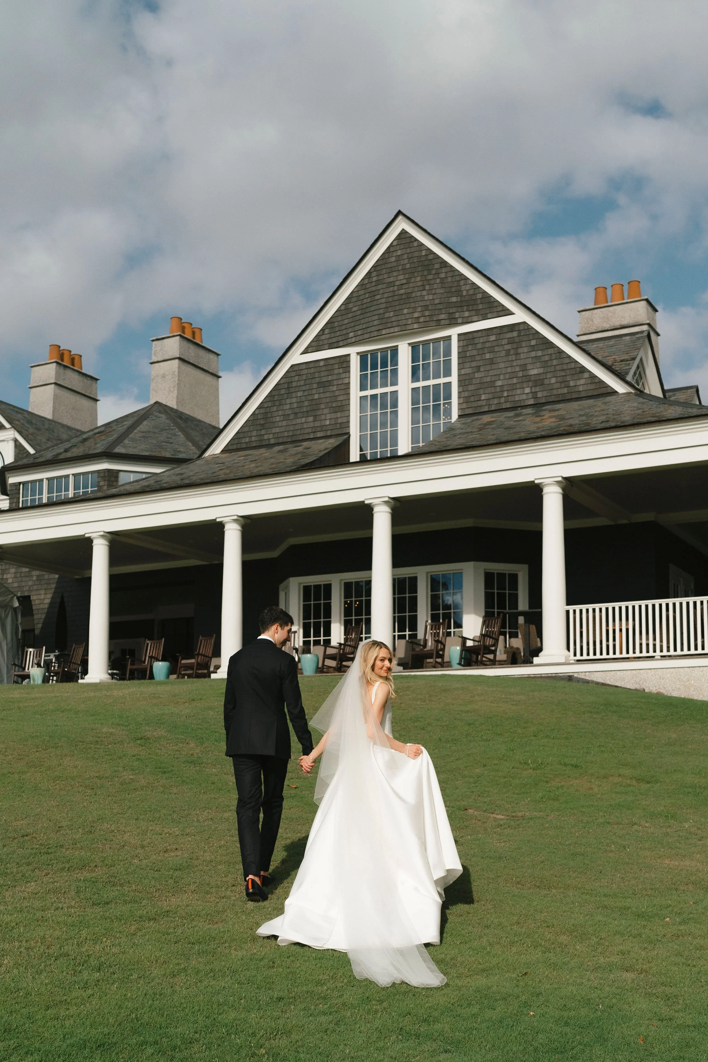 Bride and groom walking across the lawn at Kiawah River Course during a coastal wedding weekend.