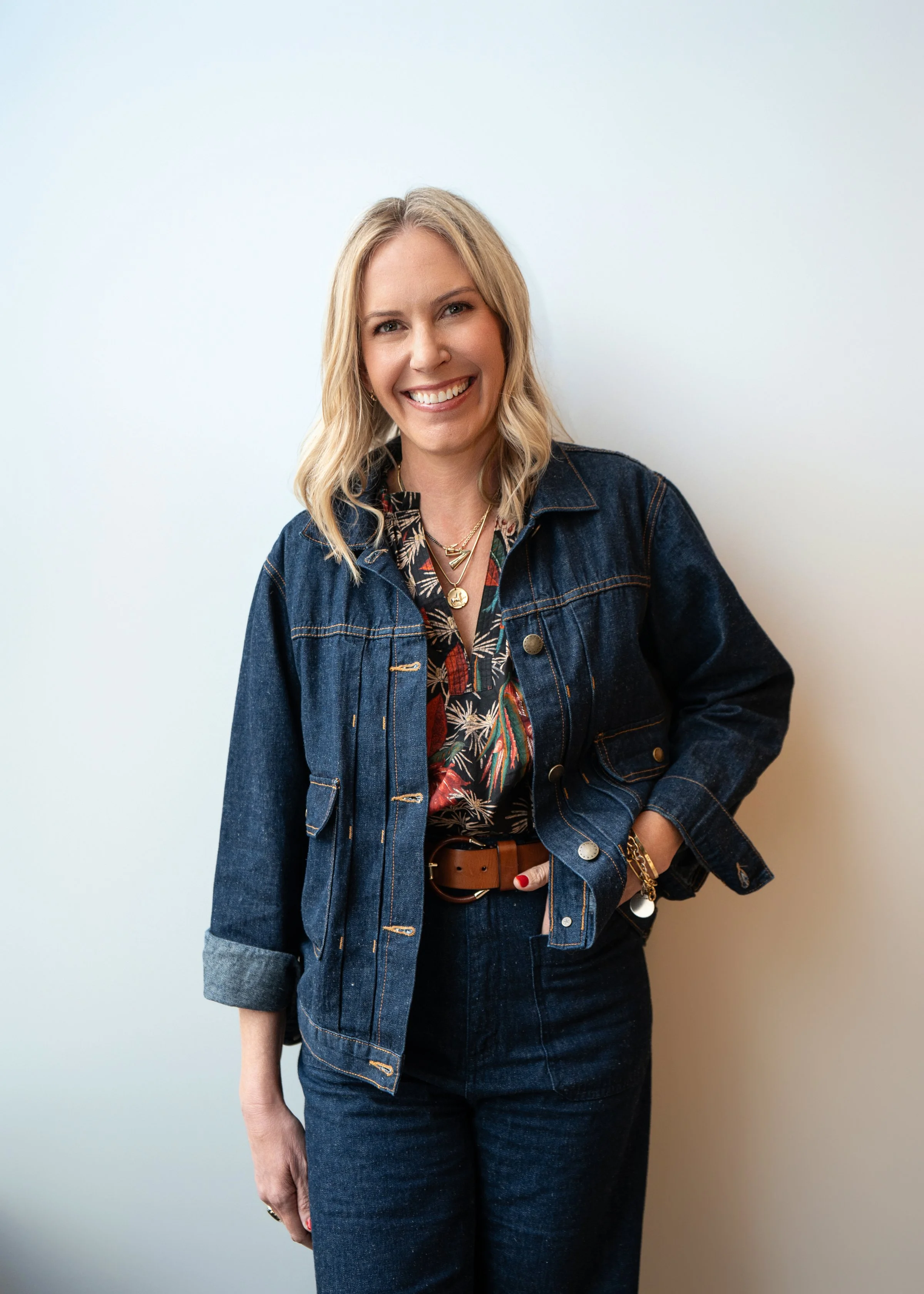 Alison Hotchkiss of Alison Events smiling in a denim jacket and matching jeans against a light neutral background.