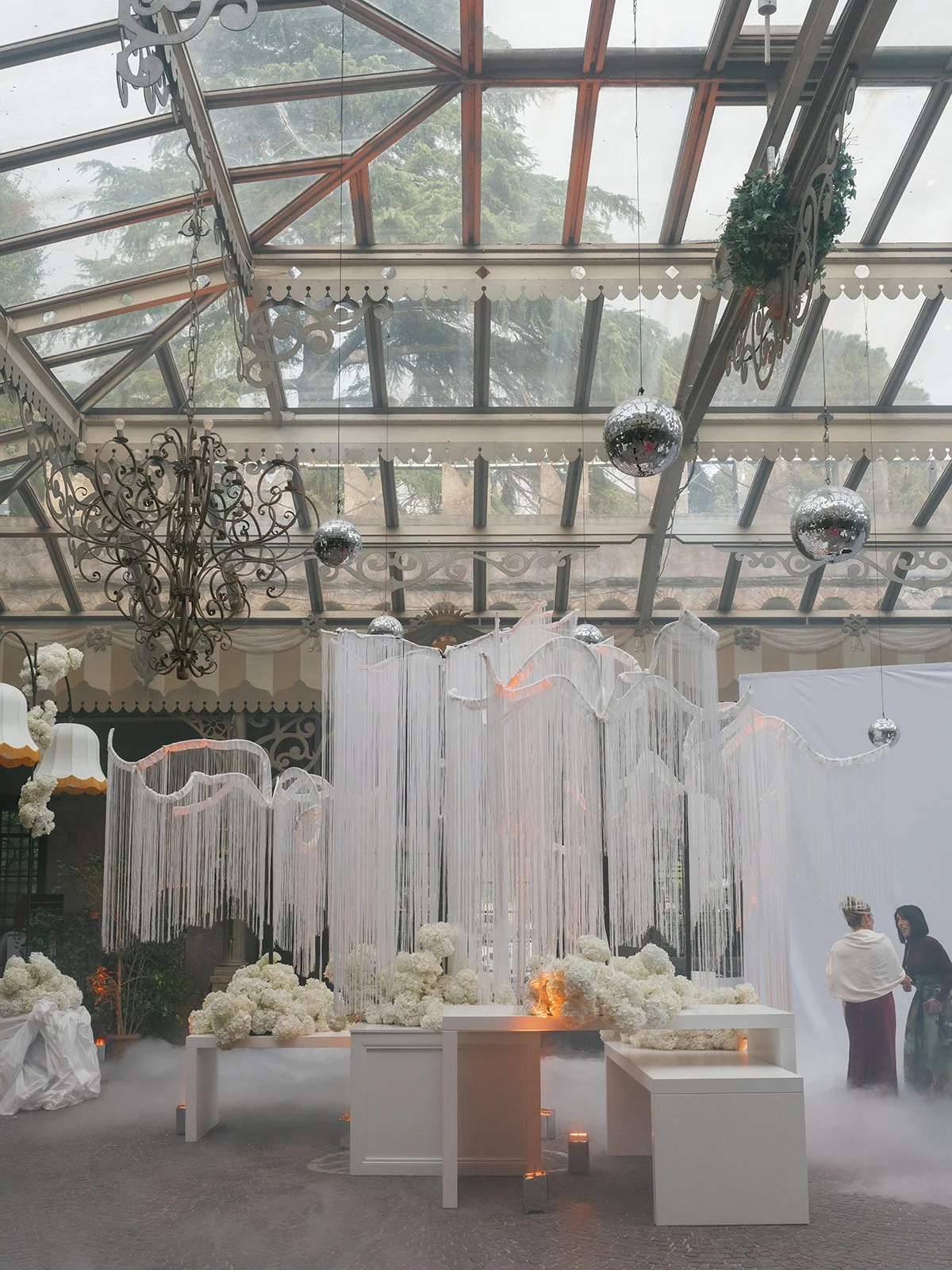 Candlelit wedding tablescape with bird of paradise florals, crystal glassware, personalized menus, and layered place settings.