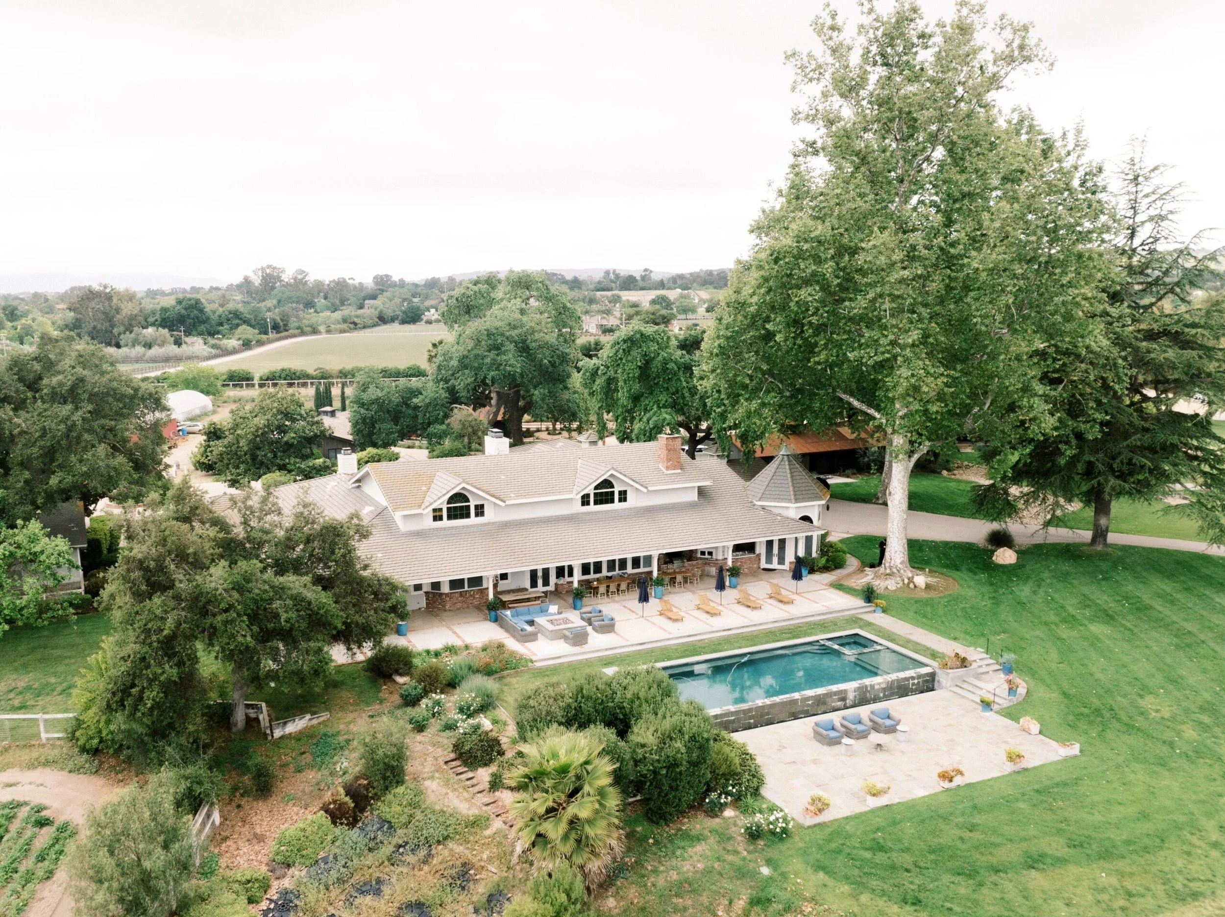 Aerial view of a Santa Barbara area private estate with a pool, patio seating, and expansive green lawn.