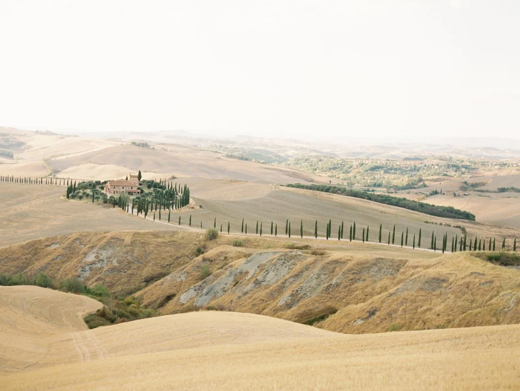 Rolling golden hills and cypress-lined roads in Val d’Orcia, Tuscany, surrounded by the Italian countryside.