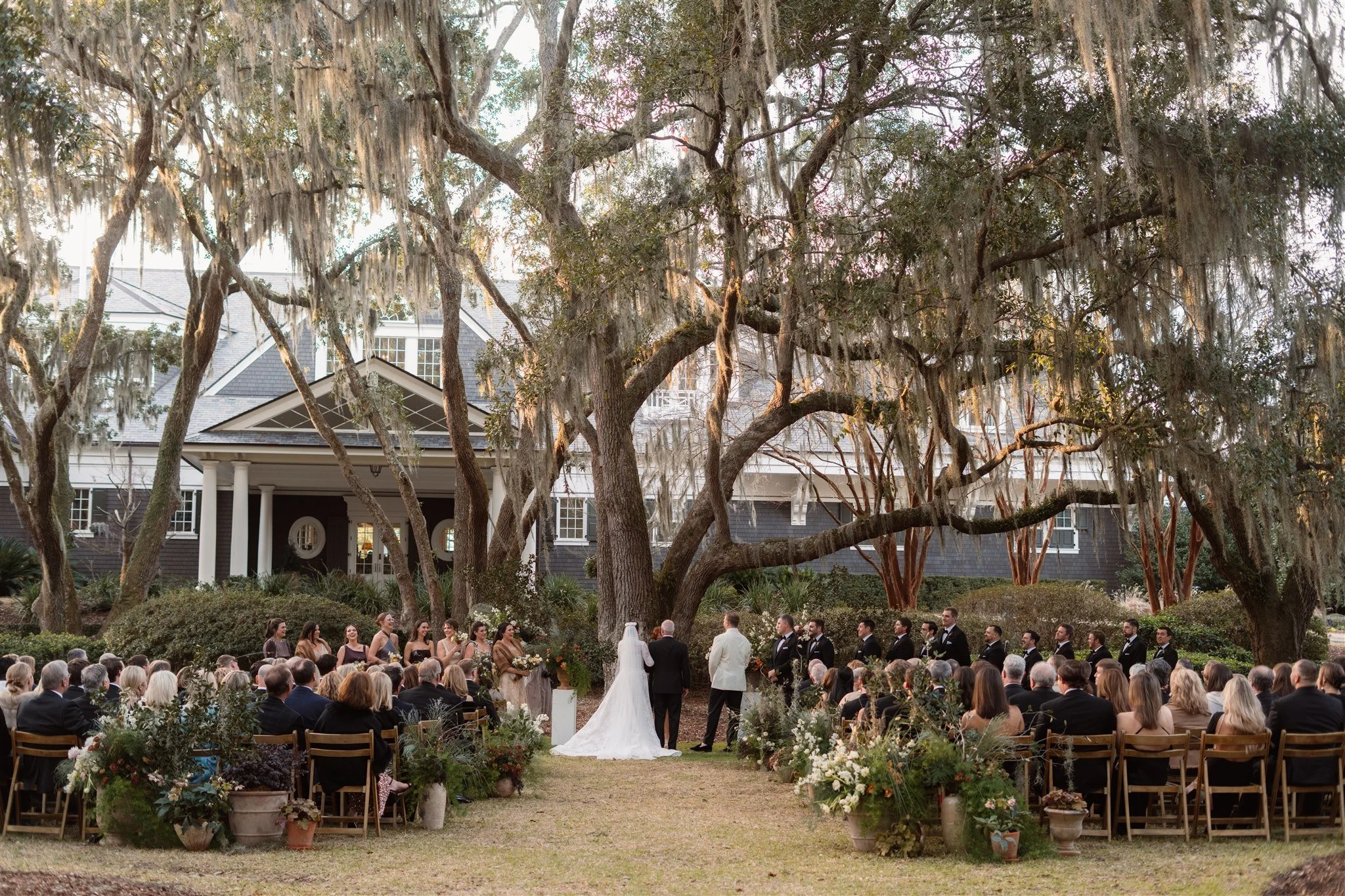 Outdoor Kiawah Island wedding ceremony beneath live oaks and Spanish moss with guests seated in the Lowcountry landscape.