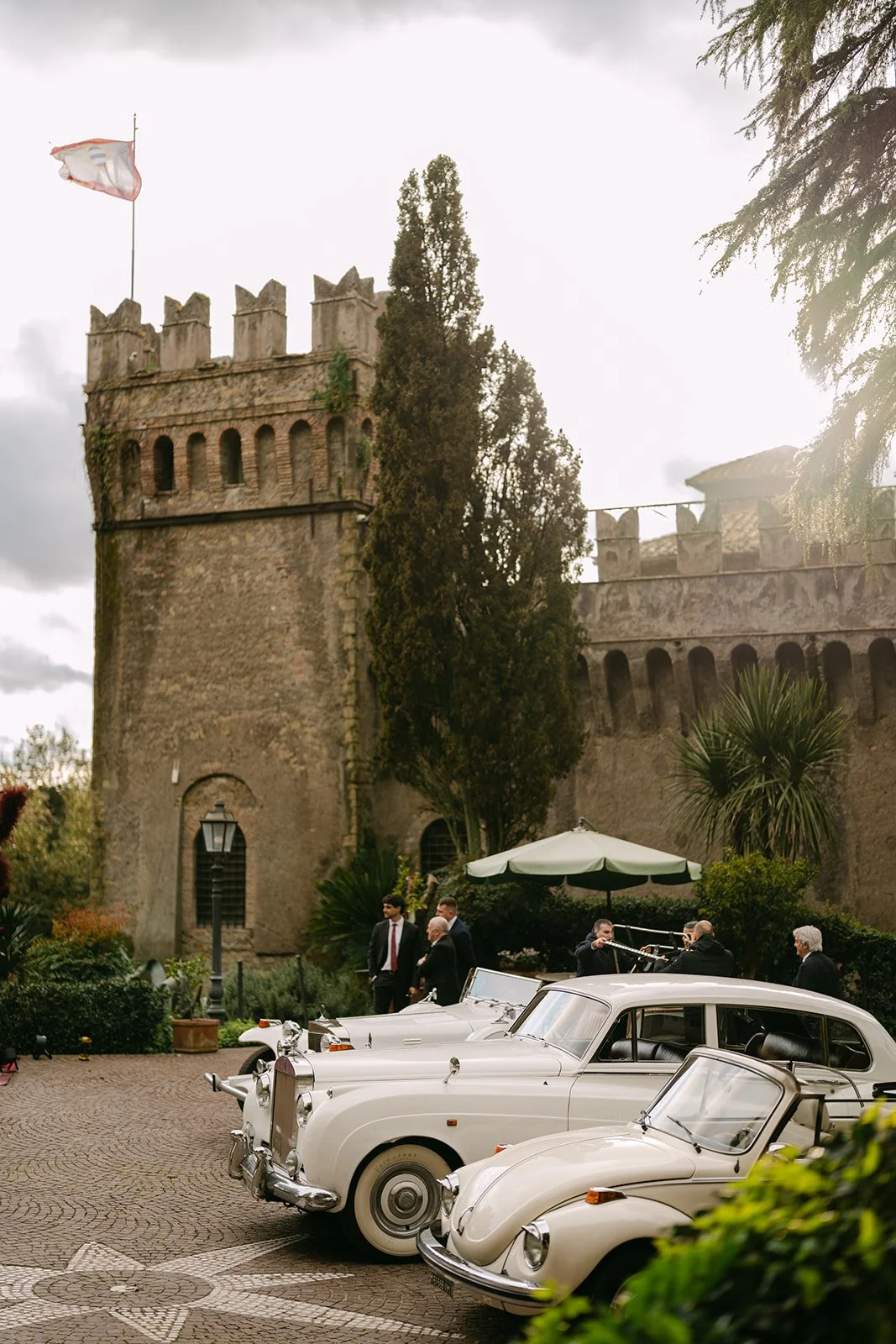 Vintage white wedding cars parked outside a historic estate in Rome, Italy, illustrating thoughtful destination wedding transportation.