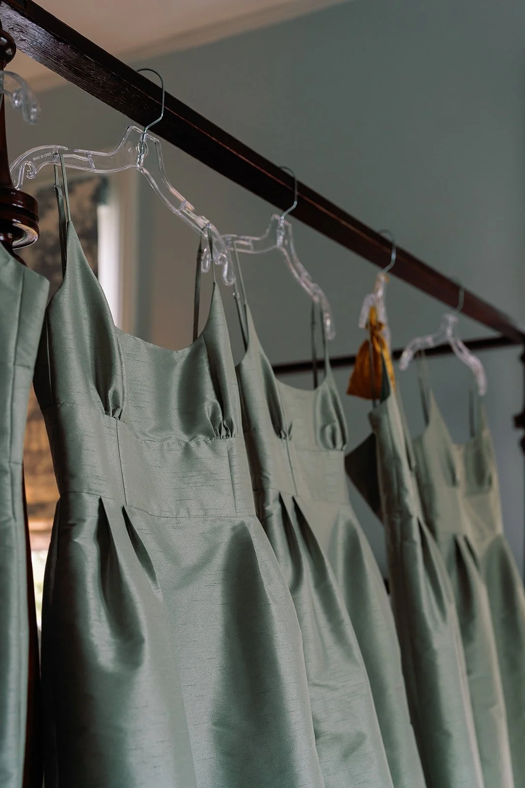Sage green bridesmaid dresses hanging together in a Charleston getting-ready suite before the wedding ceremony.