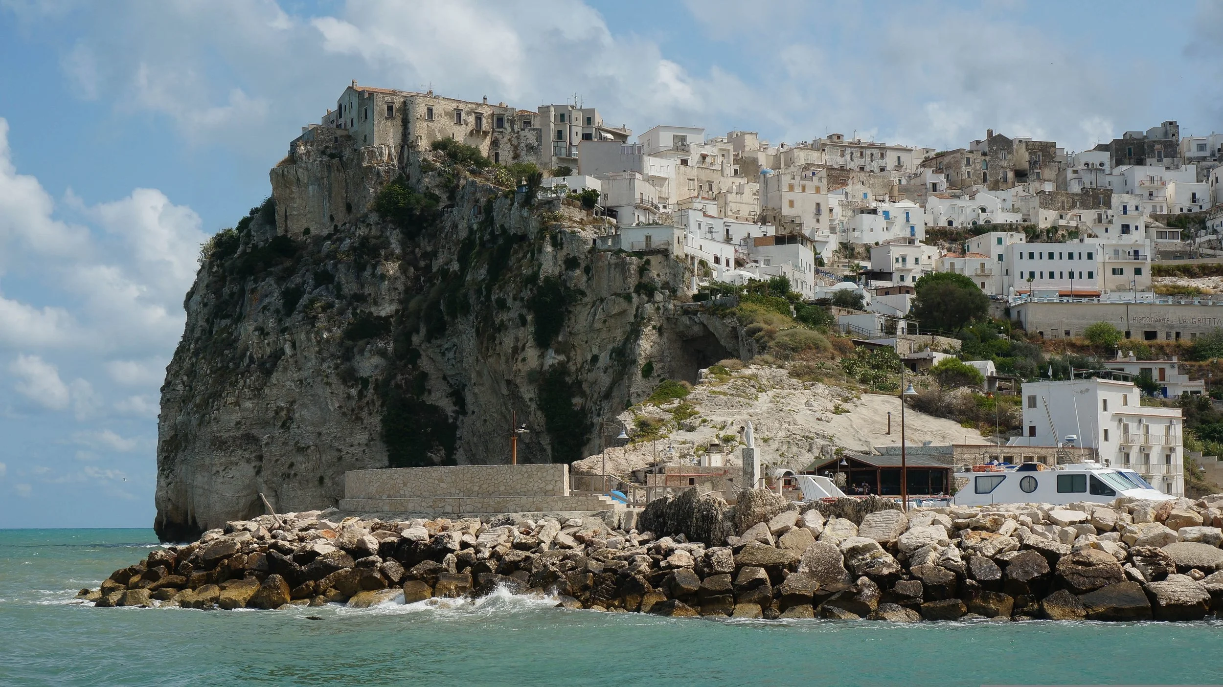 Whitewashed cliffside village in Puglia overlooking turquoise water, offering a dramatic coastal setting for a destination wedding weekend.