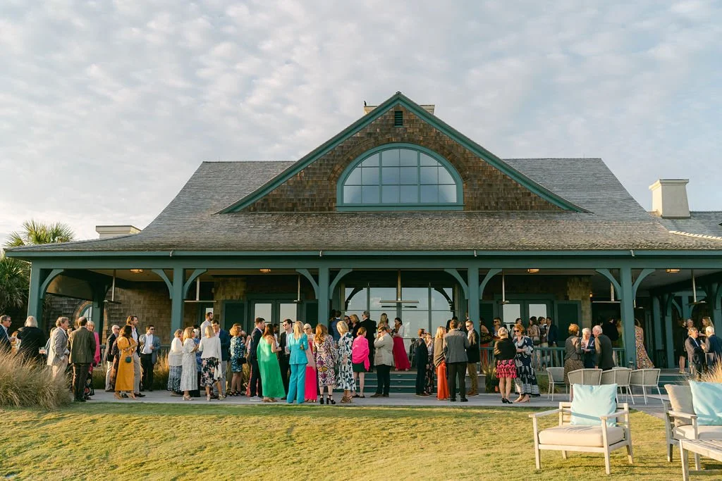 Guests gathering outside a Kiawah Island clubhouse for cocktail hour during a coastal wedding weekend.