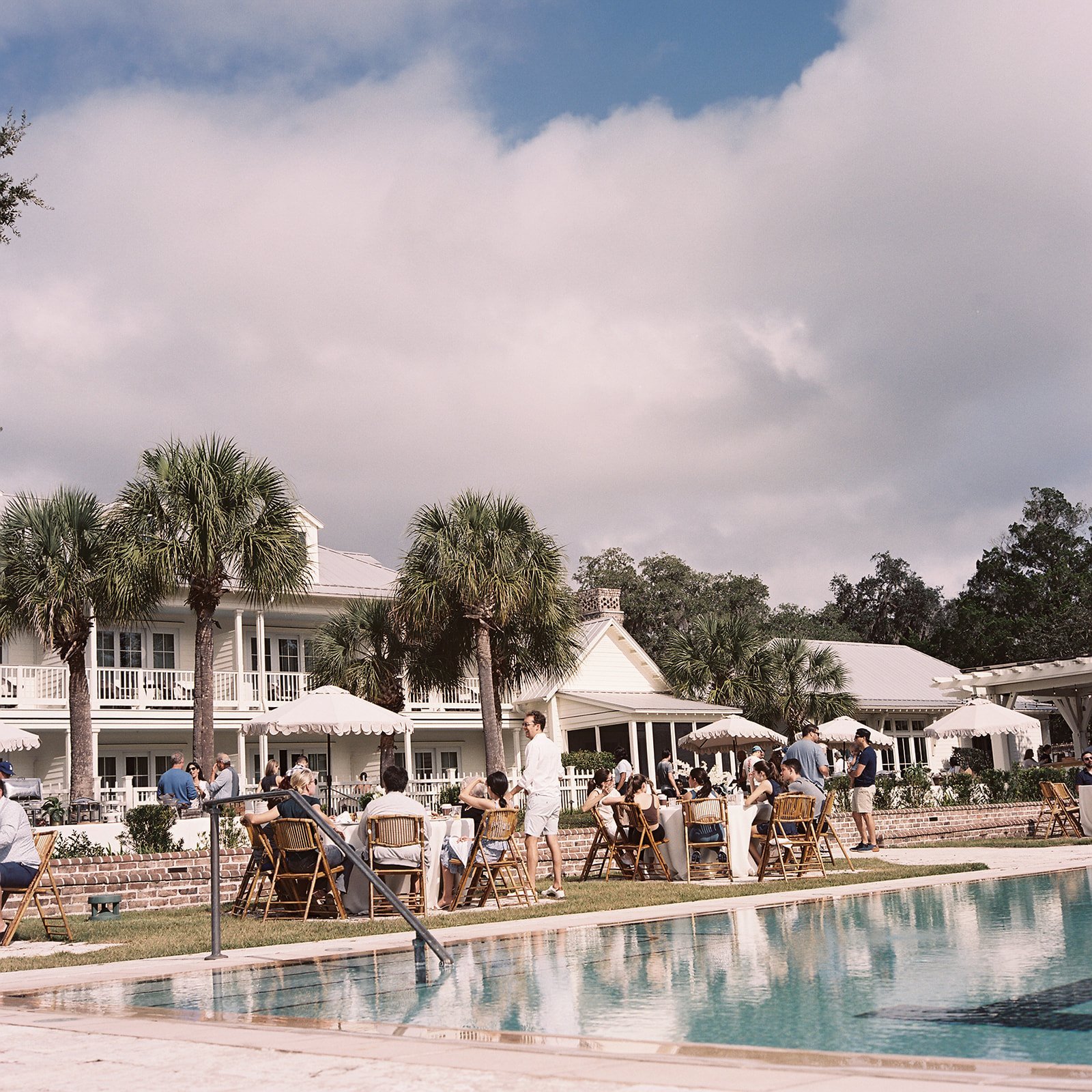 A picturesque lakefront garden party featuring round tables, floral arrangements, and guests mingling under a sunny sky.
Clark Brewer Photography
Montage Palmetto Bluff