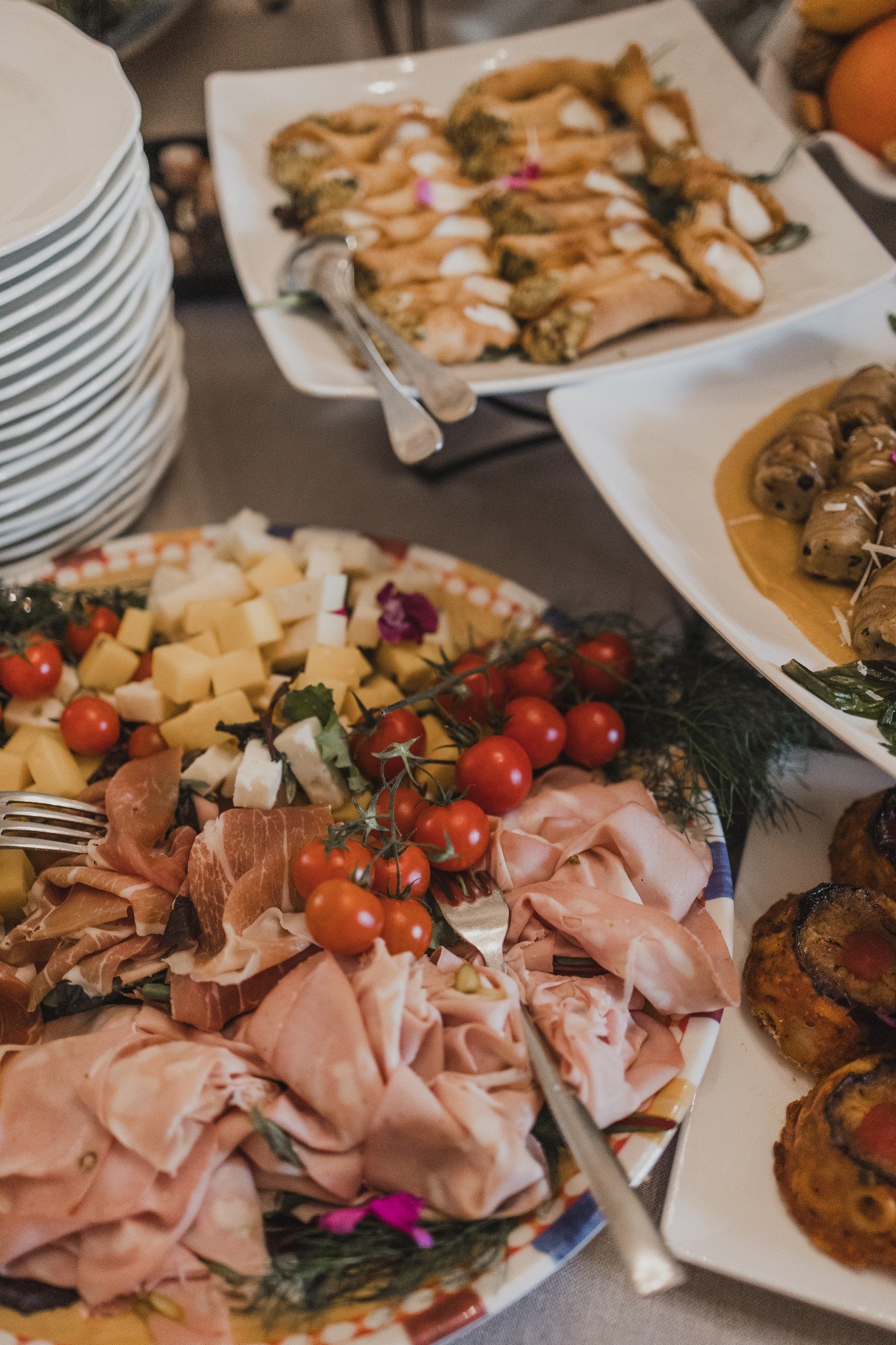 A vibrant antipasto spread with Italian cured meats, cheeses, cherry tomatoes, and fresh cannoli, styled for an elegant wedding welcome reception in Italy.