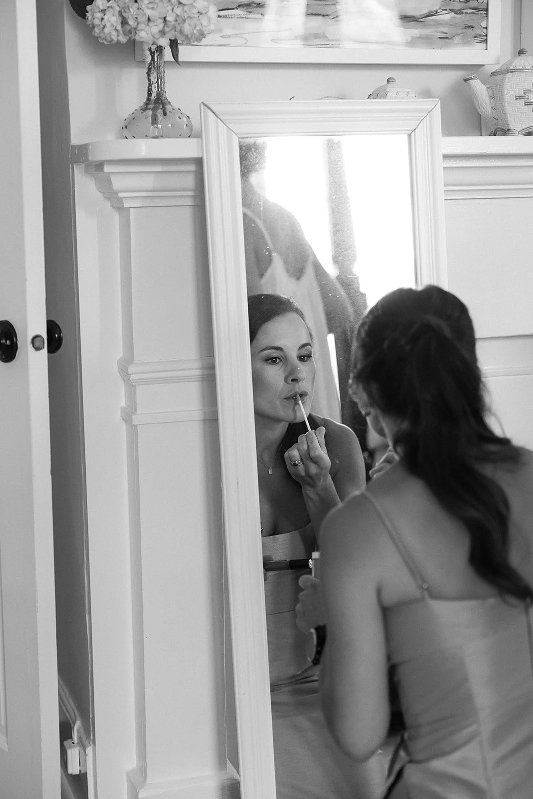 Wedding party member applying makeup in front of a full-length mirror during wedding day preparations in Charleston.