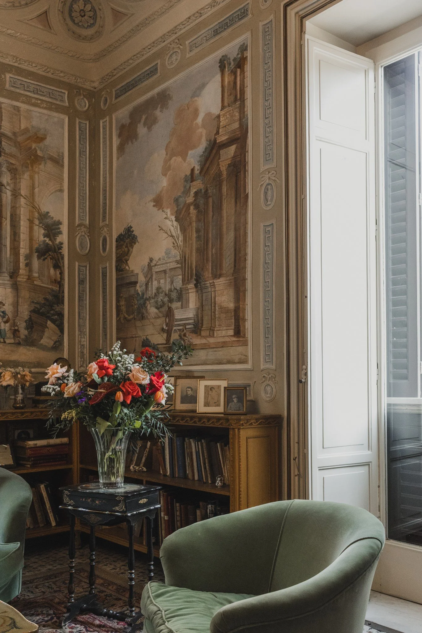 A richly detailed Italian villa interior with frescoed walls, a floral arrangement, and velvet seating, showcasing the atmosphere of historic Italy wedding venues.