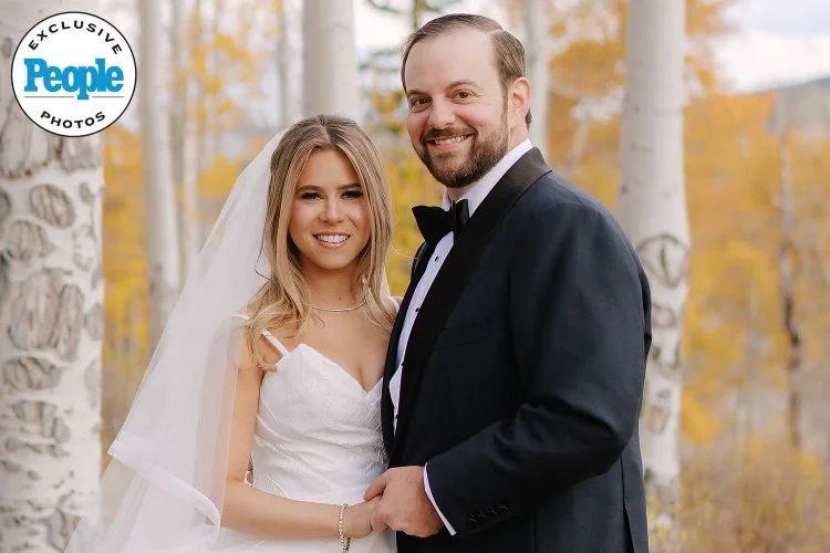 Wedding portrait of Jordan Kahn and his wife dressed in formal wedding attire outdoors among white-barked trees with autumn foliage.