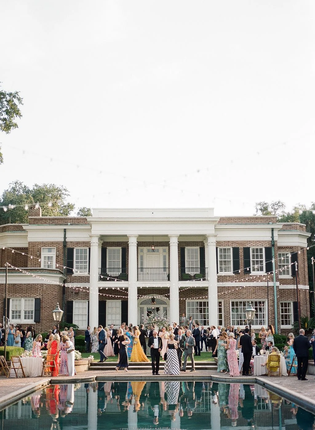 Wedding guests gathering around a reflecting pool during an outdoor reception at a Southern estate.