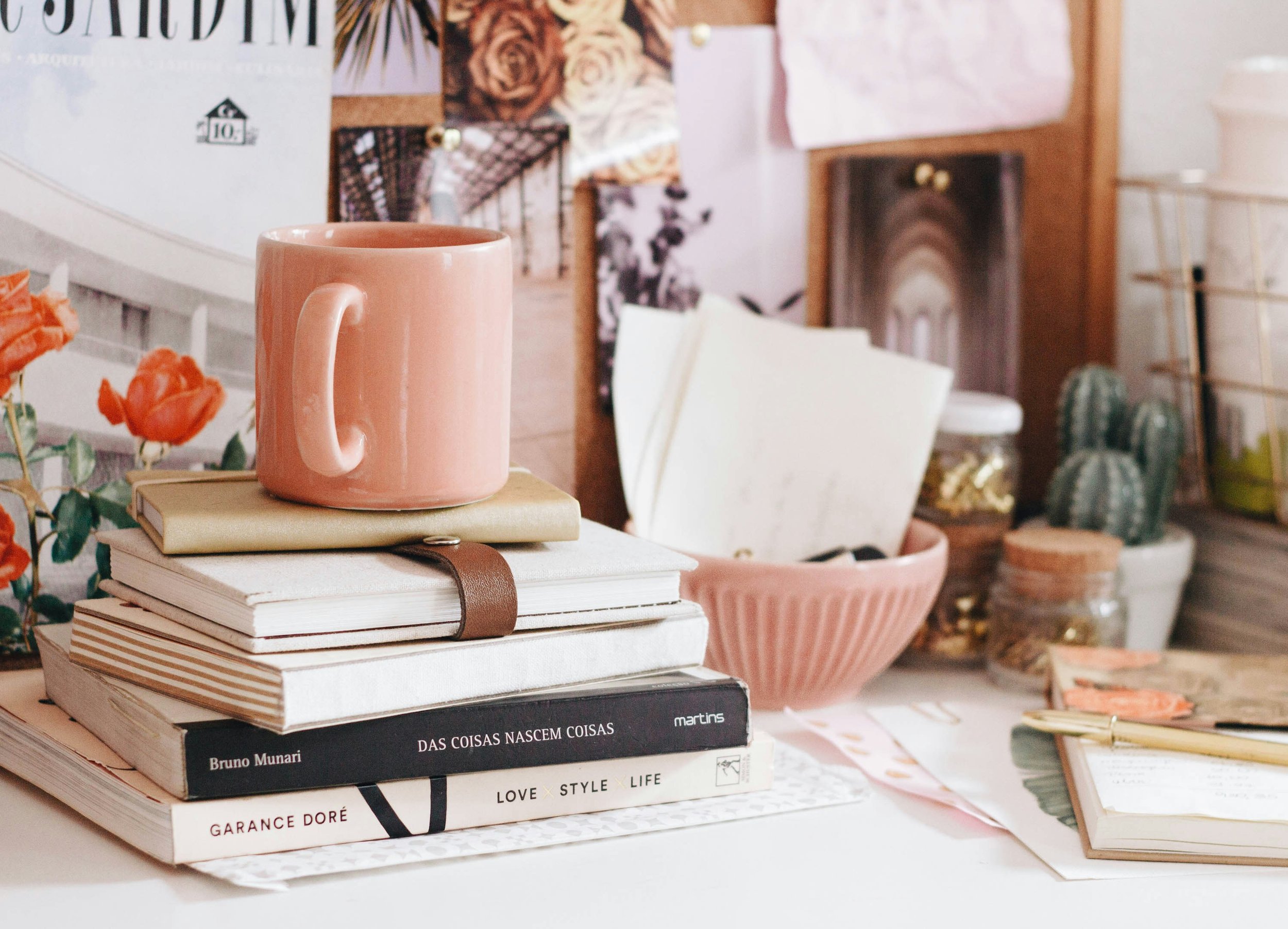 Cluttered desk with stacked books and a coffee cup, symbolizing the writing process and moments of doubt writers often face.
