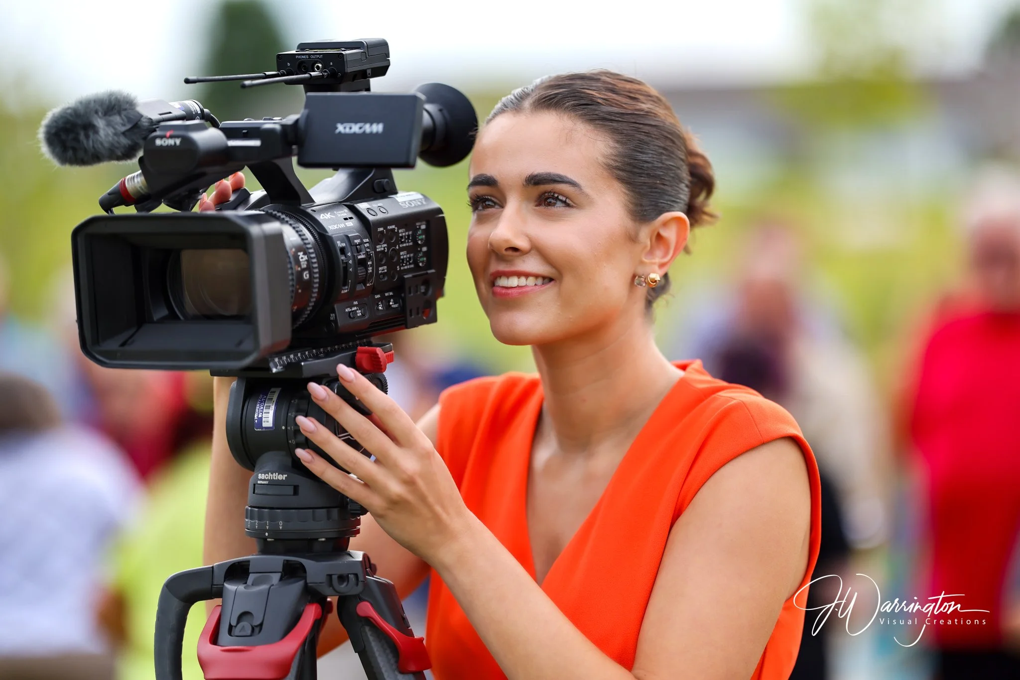 A female videographer smiling while operating a professional video camera captured by Northwest Ohio photographer