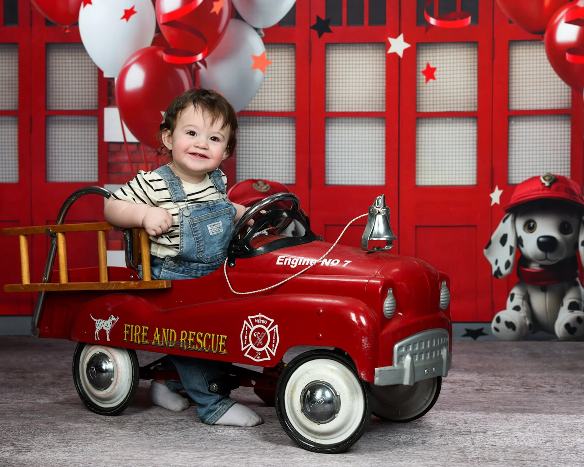 Creative milestone portrait of a smiling baby boy sitting in a red vintage toy fire truck, captured by northwest ohio photographer 
