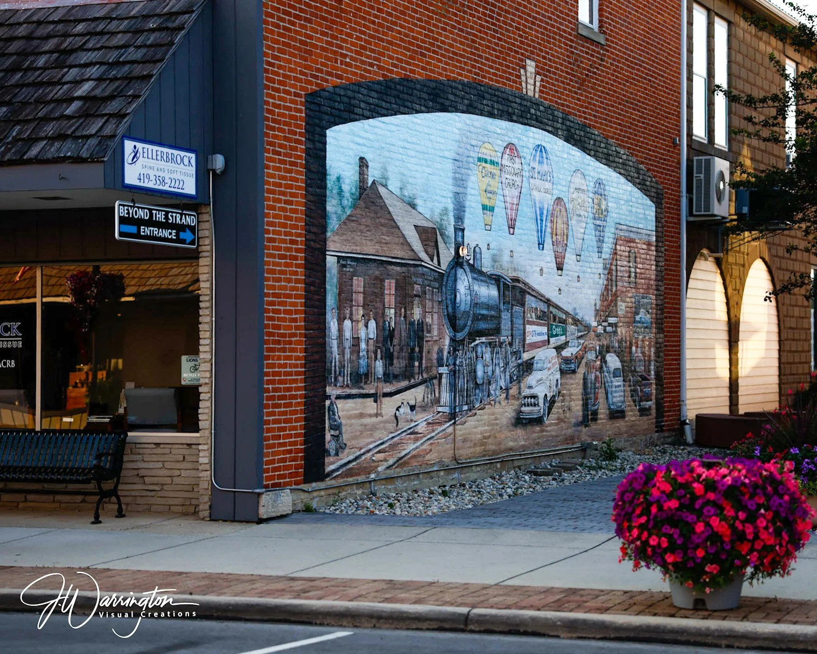 Historical mural in Downtown Bluffton, on building brick wall depicting a steam train, people, cars, and hot air balloons in a vintage style.