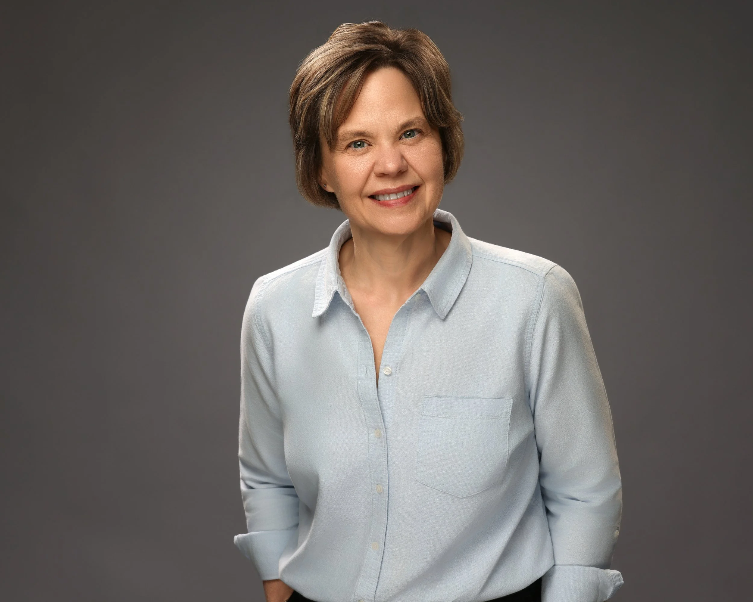 Female Executive smiling against a gray background.