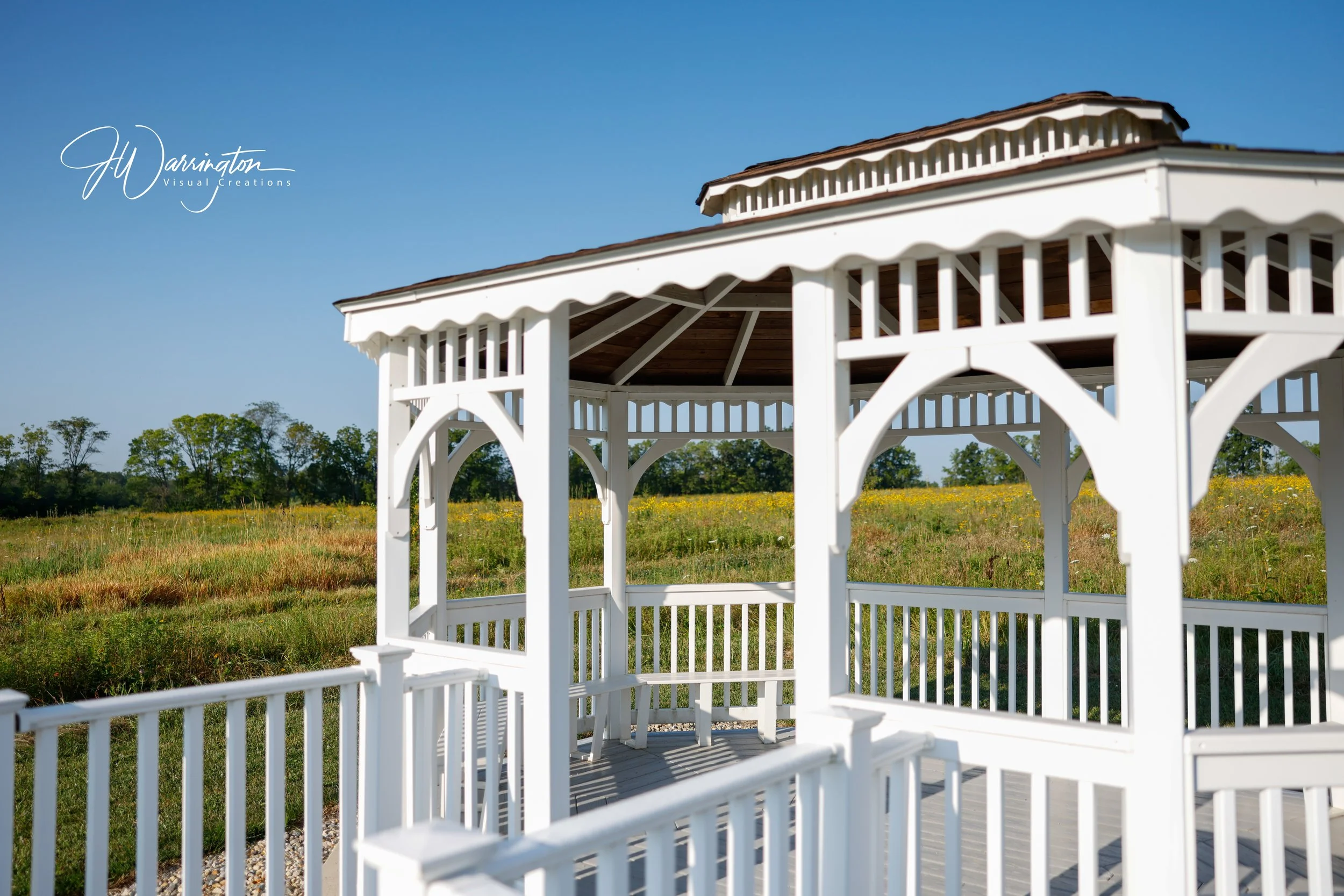 White gazebo on a grassy field with trees and blue sky in the background at Motter Metro Park, Bluffton, Ohio.