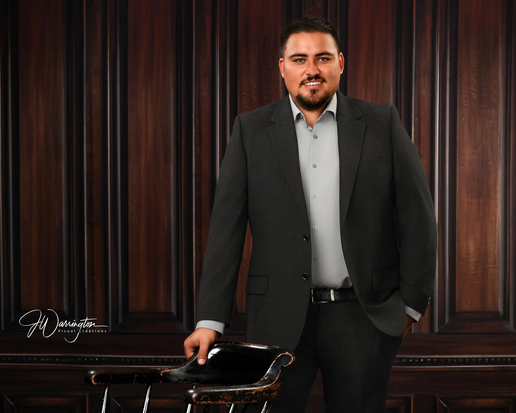 Executive branding headshot on dark mahogany paneled wall.