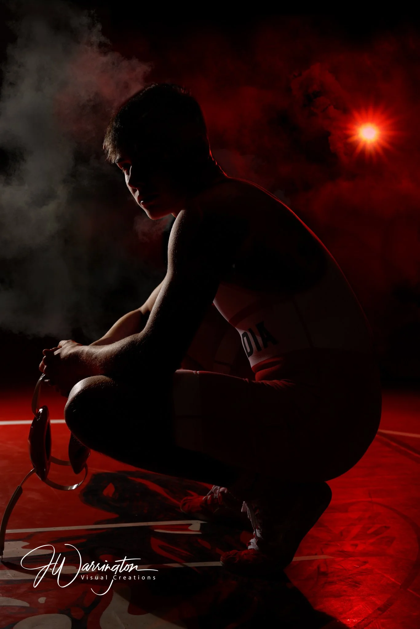 High school senior boy wrestler posing in dramatic, low-lighting conditions 