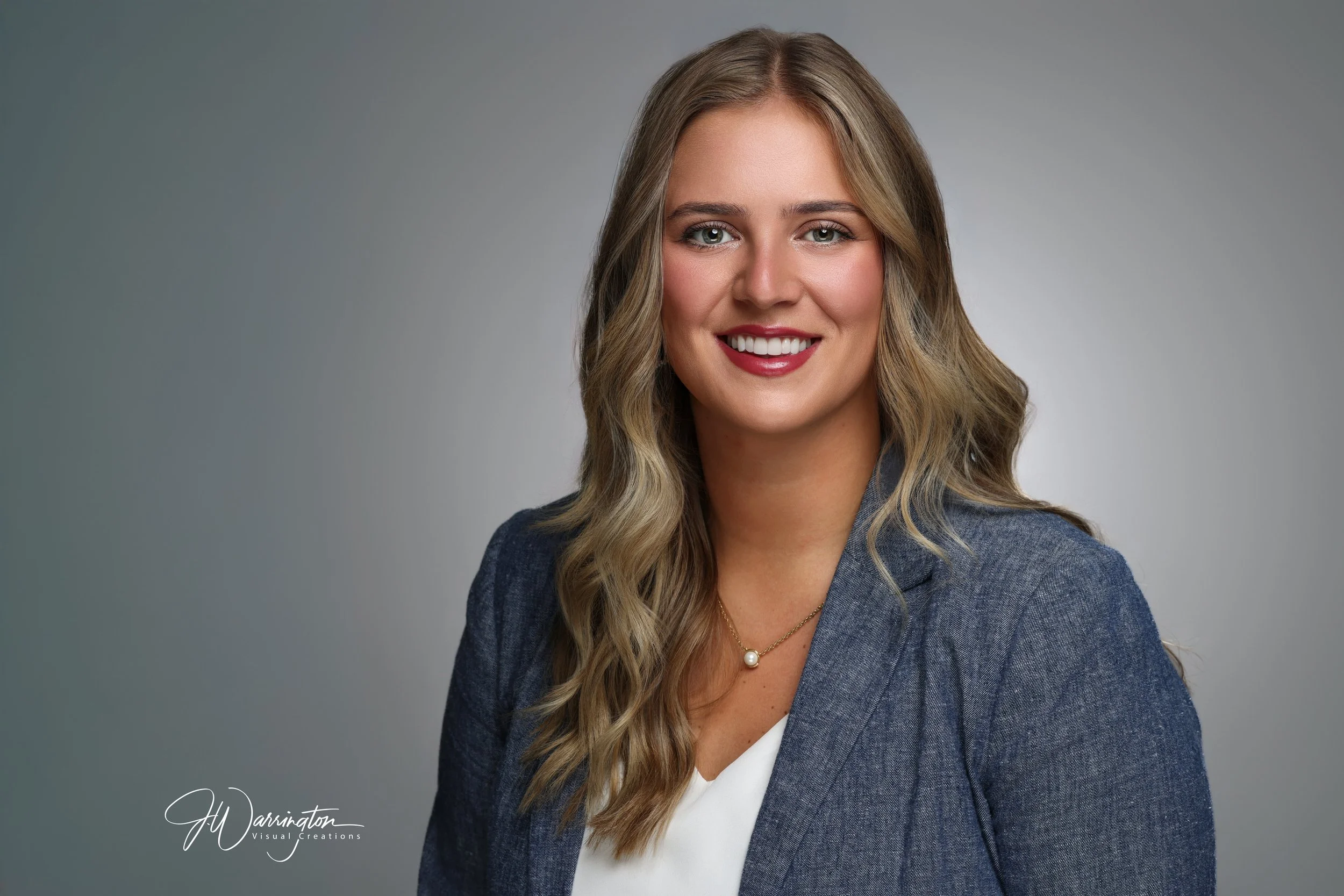 Blonde female professional headshot gray background.