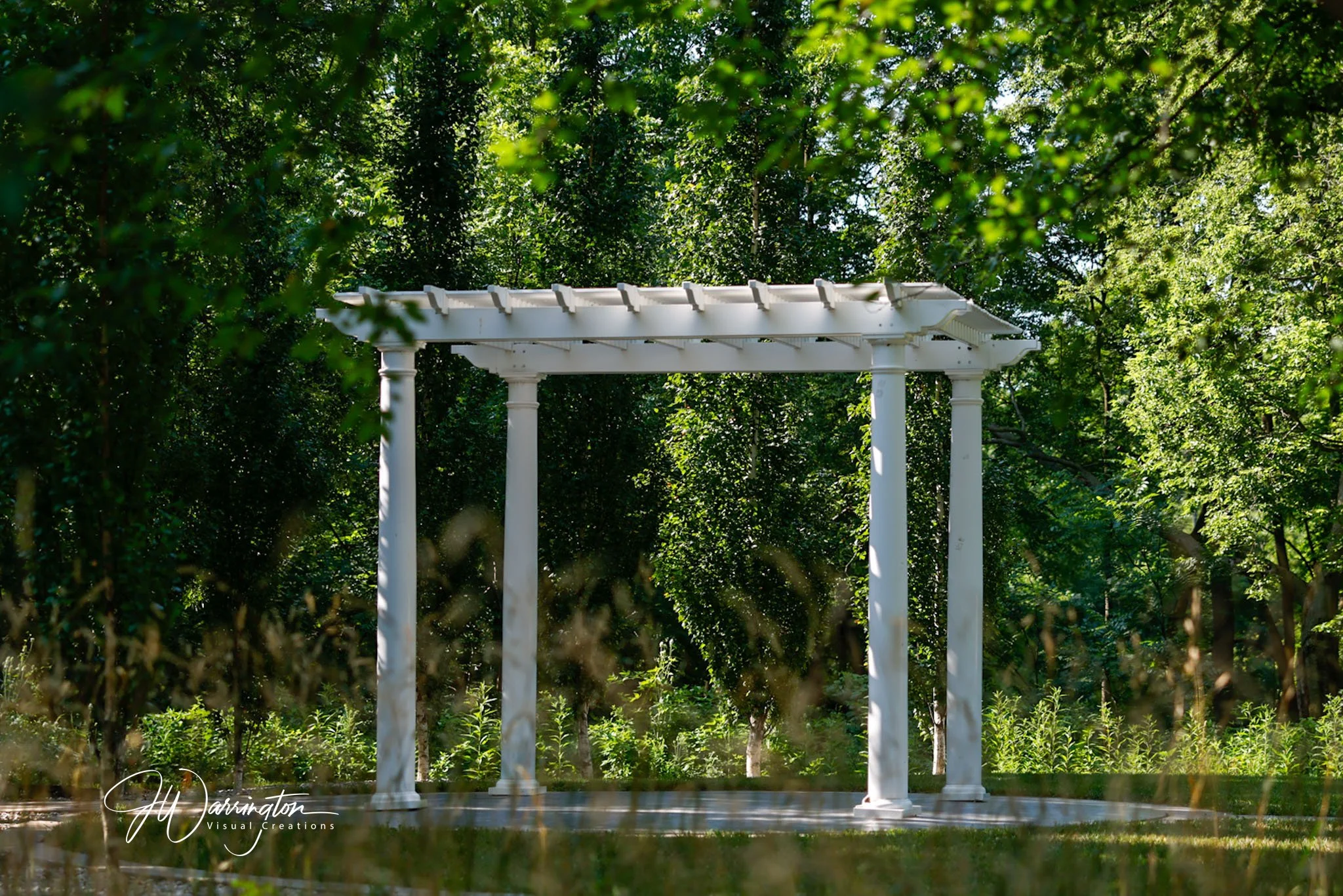 Lauer Historical Farm, White garden arch with columns surrounded by green trees and bushes