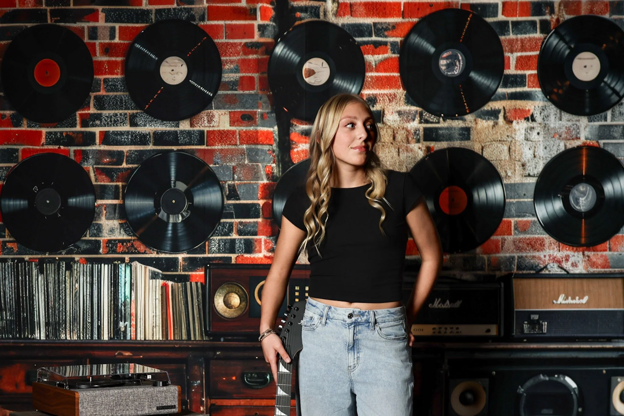 Retro studio of a teenage girl standing in front of a wall of vintage vinyl records captured by northwest ohio photographer 