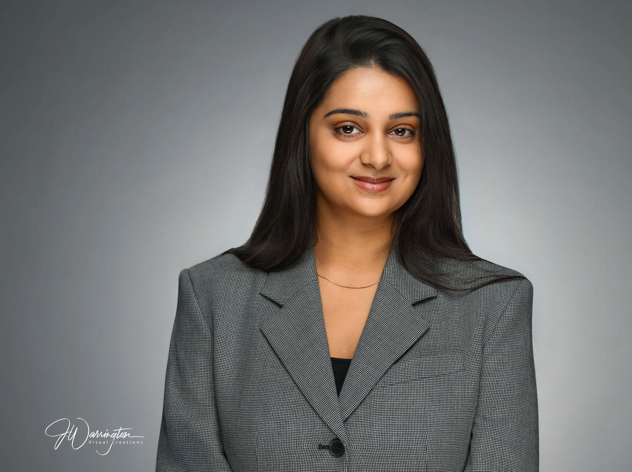 Dark hair female medical professional headshot gray background.