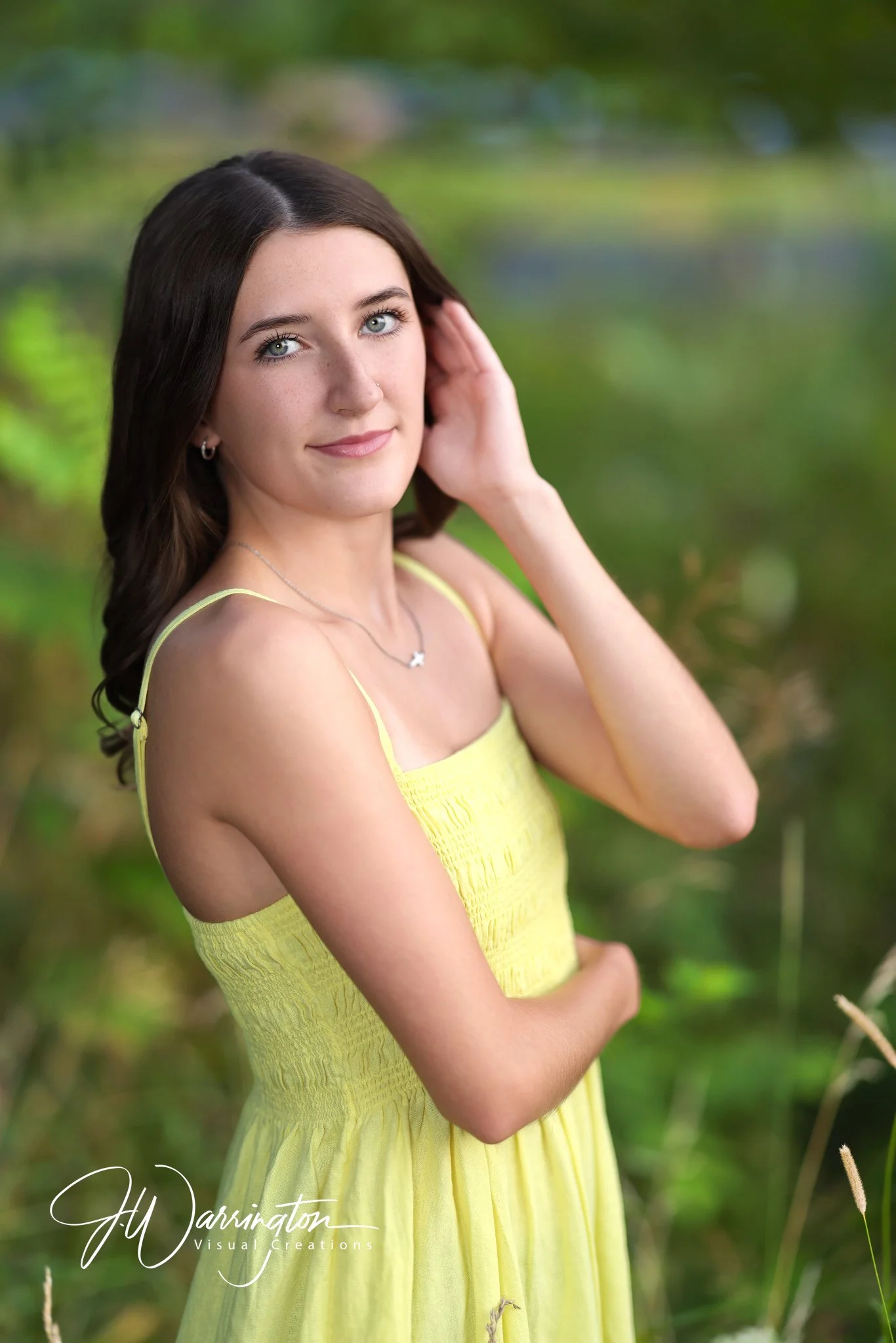 Senior girl smiling outdoors in a vibrant yellow dress during a summer nature portrait session