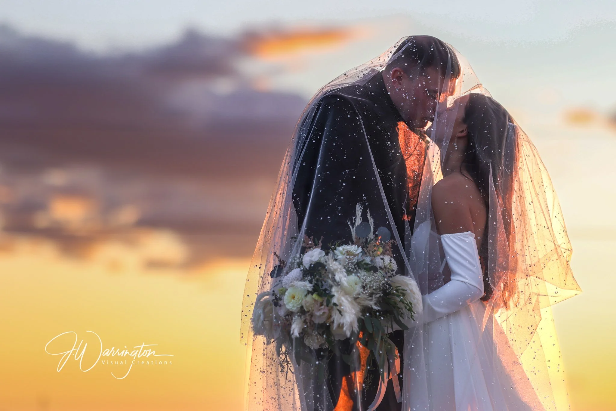 Bride and Groom at sunset kissing.