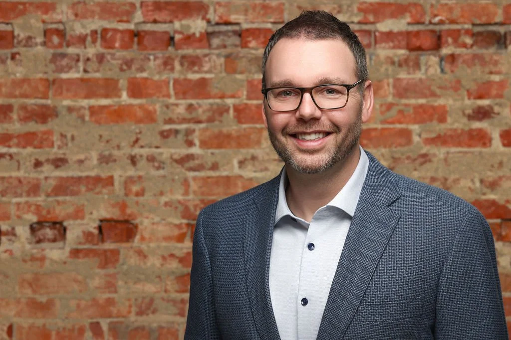 Male corporate headshot with exposed brick backdrop captured by northwest ohio photographer