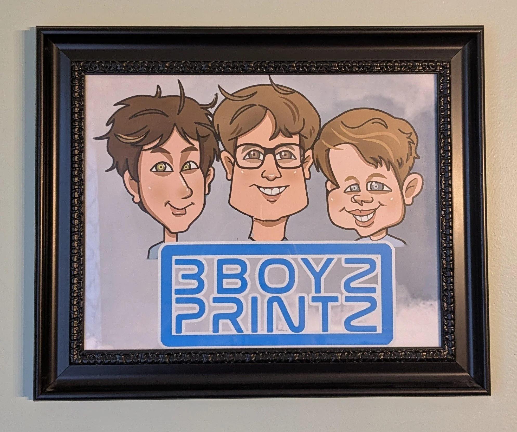Framed caricature portrait of three boys with a sign that says "3 BOYS 3 PRINT"