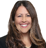 Portrait of a smiling woman with long brown hair, wearing a black blazer and white shirt.