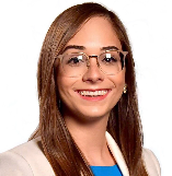 A woman with long brown hair and glasses smiling, wearing a blue and white outfit.