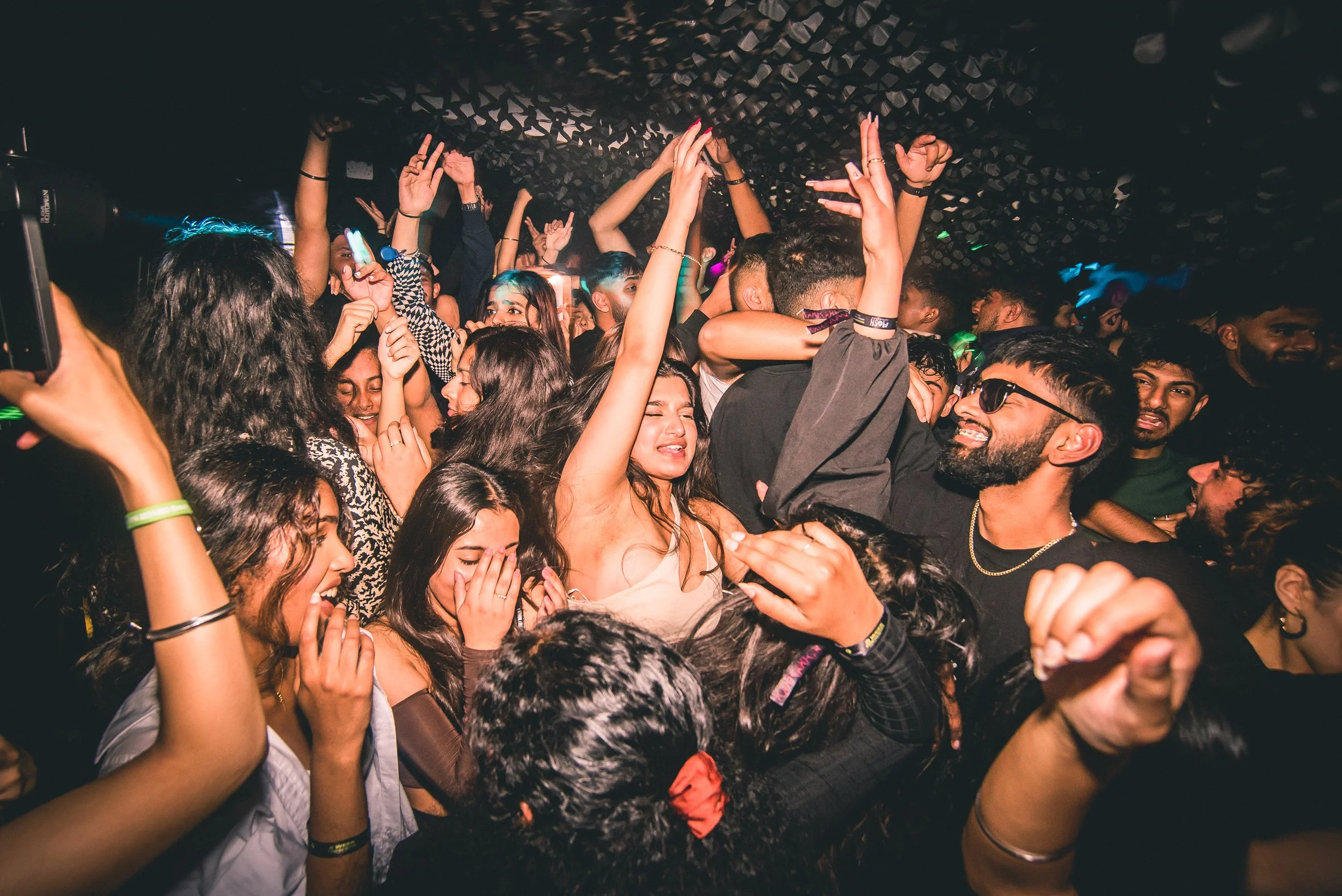 A crowded dance floor at night with group of people dancing and enjoying music.
