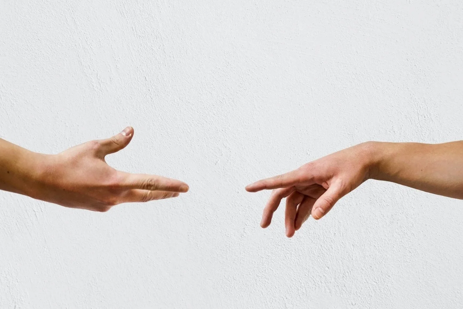 Two hands reaching toward each other, one on the left and one on the right, against a white textured background.