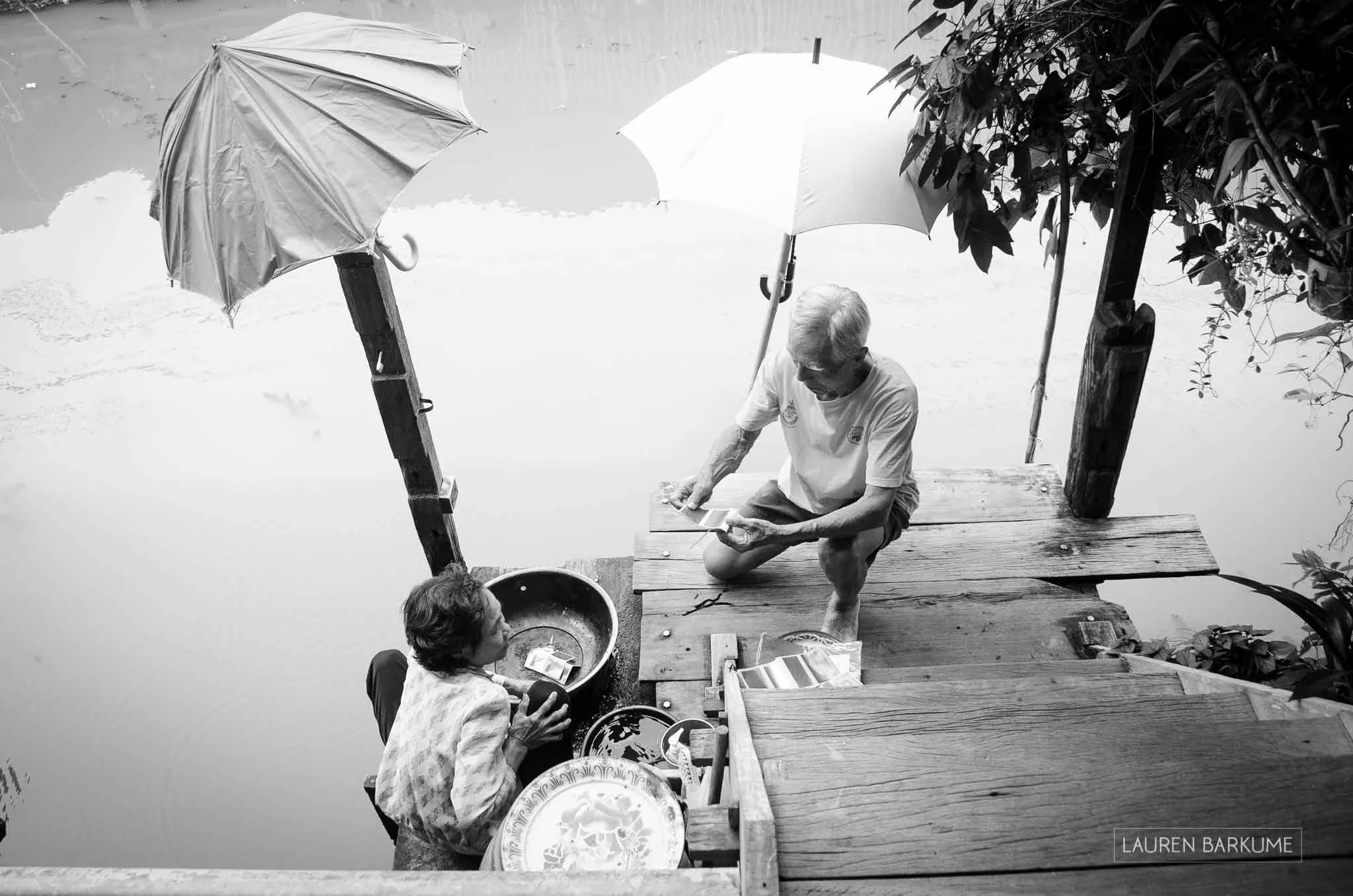 A couple burn an offering of paper money on the front step of their stilted home near the Damnoen Saduak floating market.