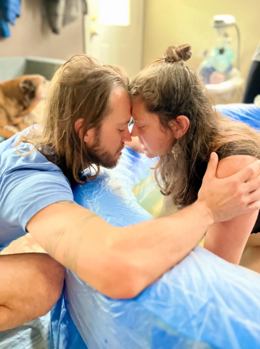 Image of Jessica Ghantous in birthing tub with forehead pressed to partner's.
