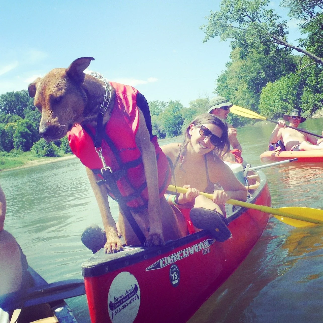 Image of Jessica Ghantous in red canoe with yellow paddle behind dog.