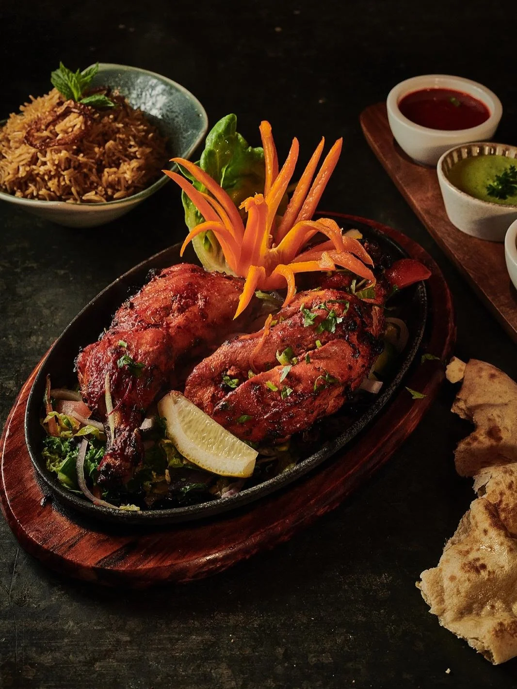 Tandoori Chicken, the proper way.

Half chicken marinated in yoghurt, rock salt, lime, mustard and our own house spices, then into the tandoor and cooked fresh to order. Charred on the outside, tender inside, served sizzling to your table.