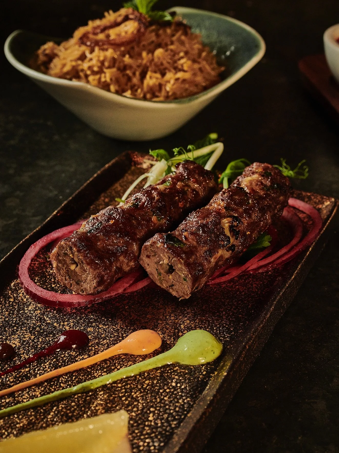 Hand-shaped seekh kebabs made with
minced lamb, fresh herbs and warming spices, grilled over open flame for a beautifully charred exterior and
succulent centre.