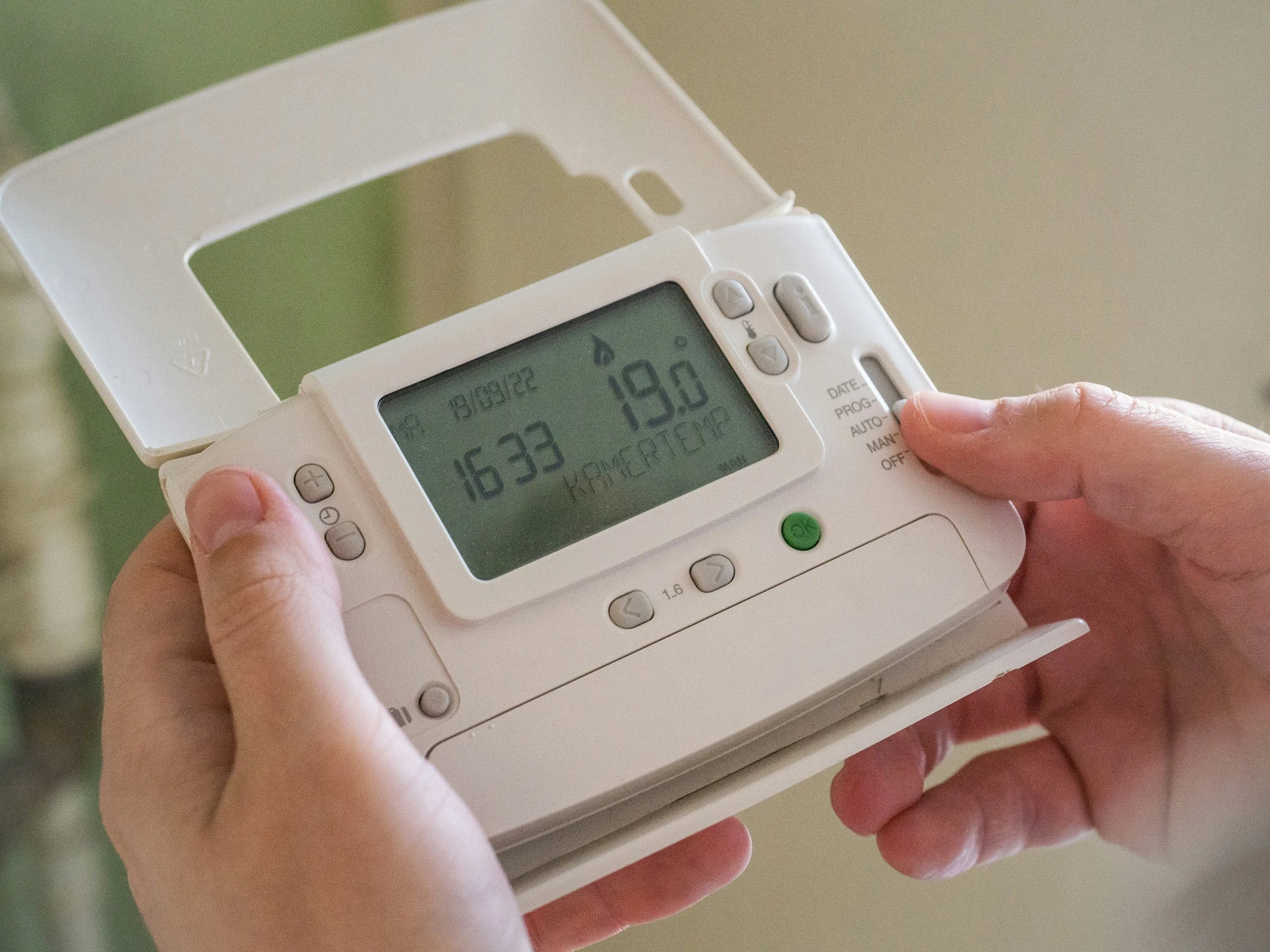 A person holding a digital blood pressure monitor displaying 163/80 mmHg, with the time 19:33 and the date 18/12/2022.