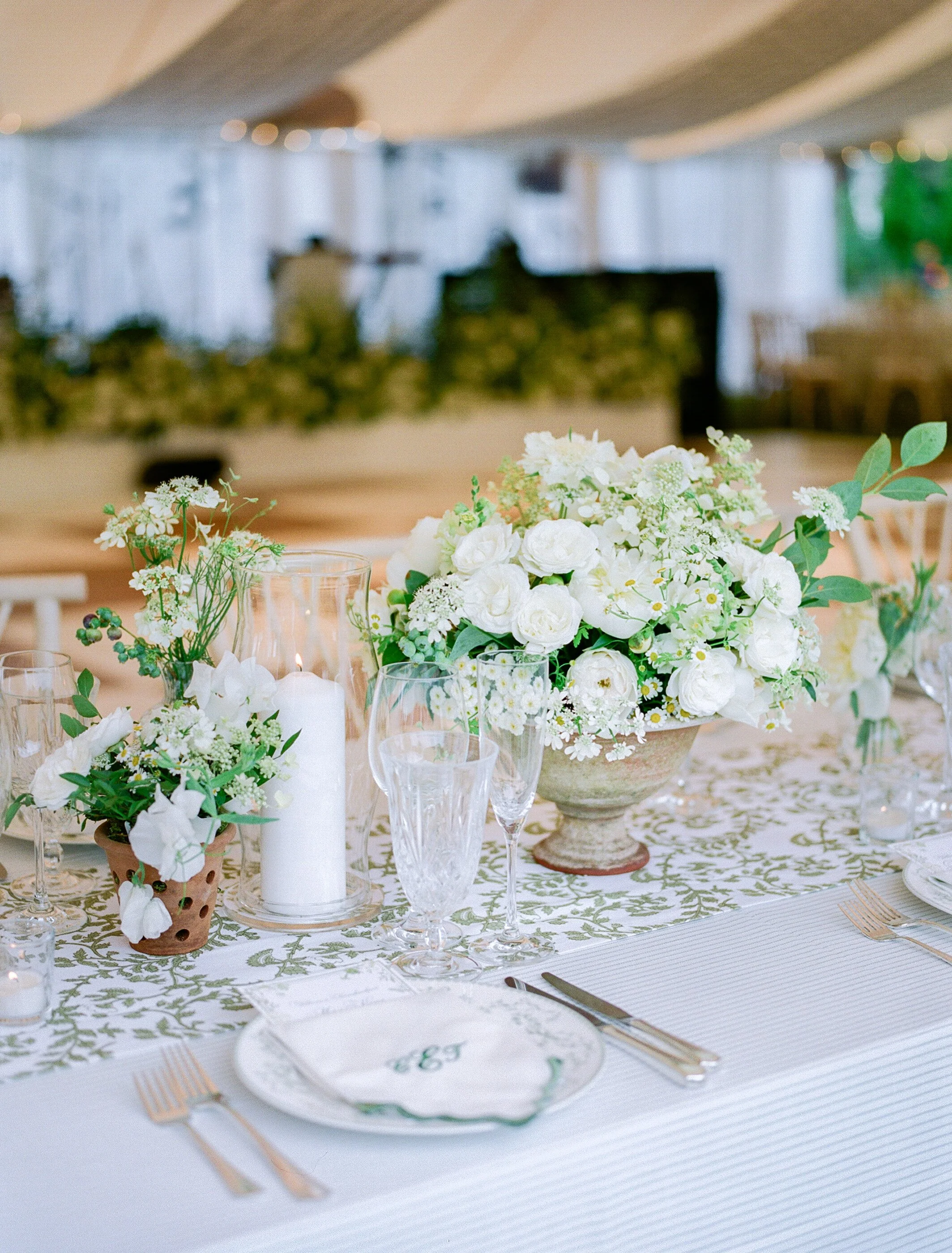 Elegant tablescape with white floral arrangements, candles, and glassware at a wedding or formal event.