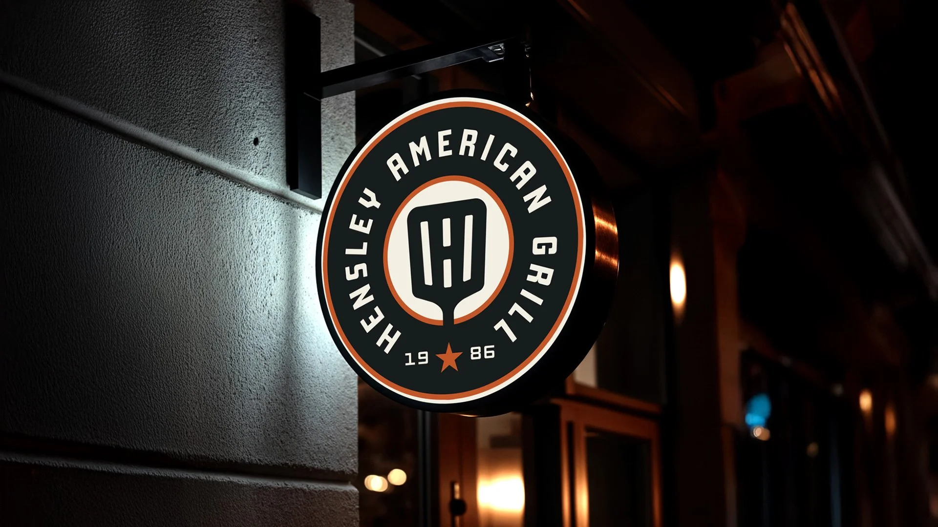 Round hanging sign for Hensley American Grill featuring a vintage badge logo and spatula icon