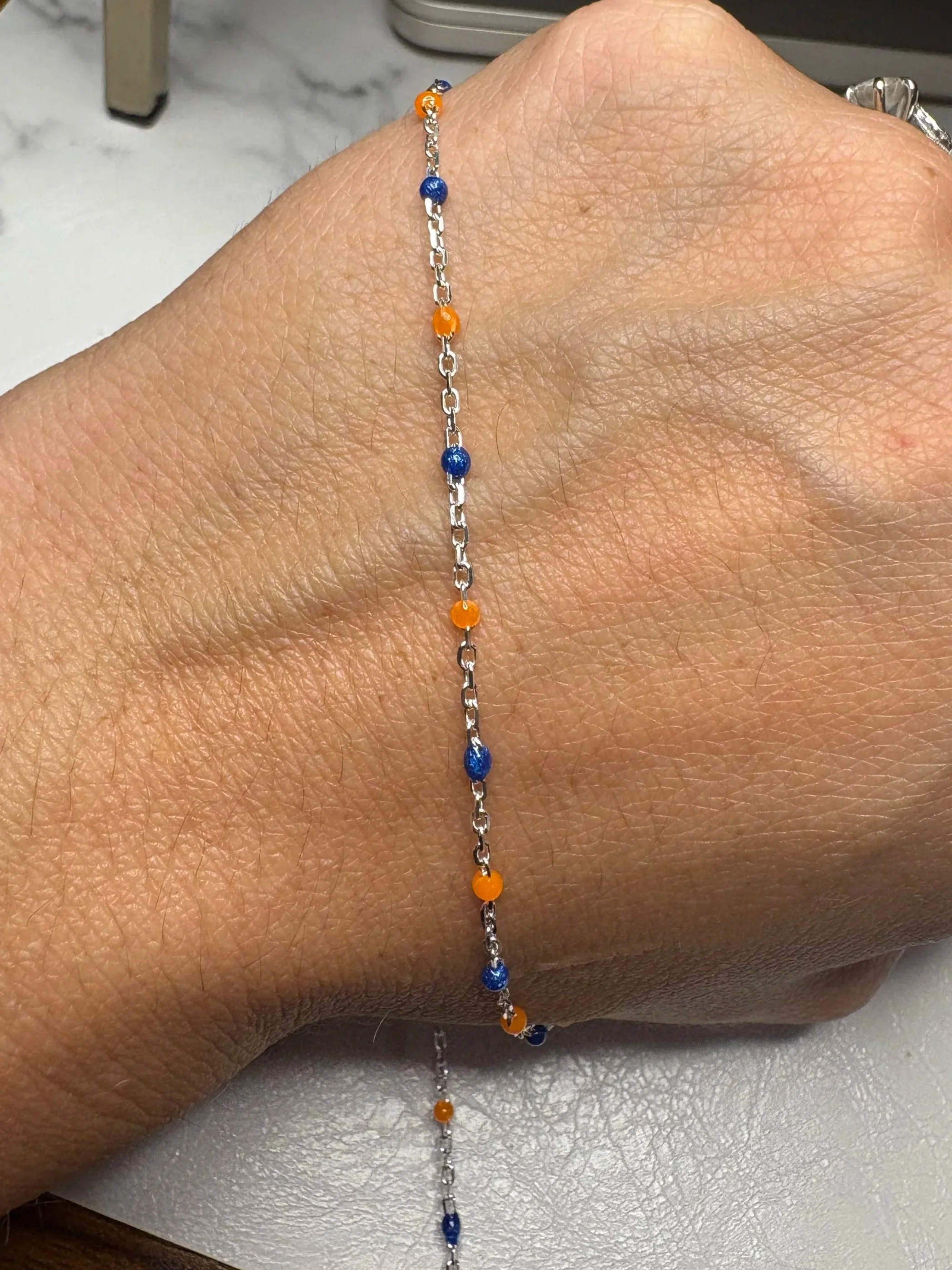 Dainty sterling silver permanent jewelry chain with small blue and orange enamel balls