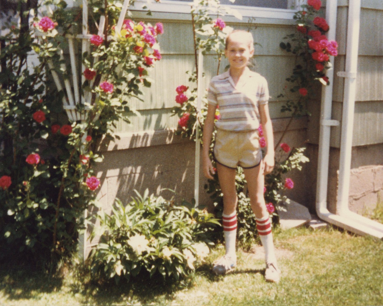 Cheryl standing by Dad's rose bushes, 1980