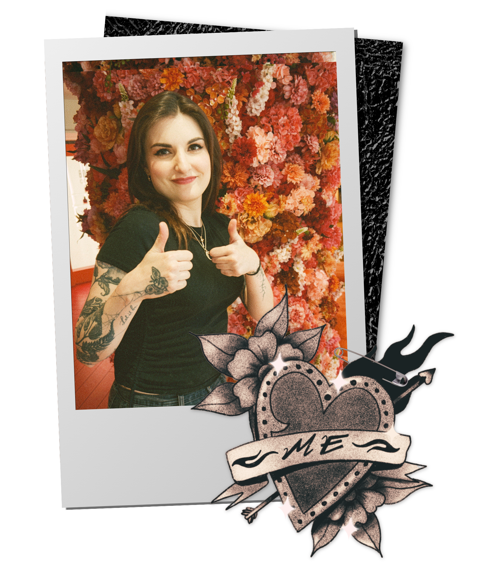 A woman with dark hair, tattoos on her left arm, wearing a black shirt, smiling and giving two thumbs up in front of a floral backdrop of pink, red, and orange flowers. The image has a Polaroid-style border and decorative overlay of a rose and banner