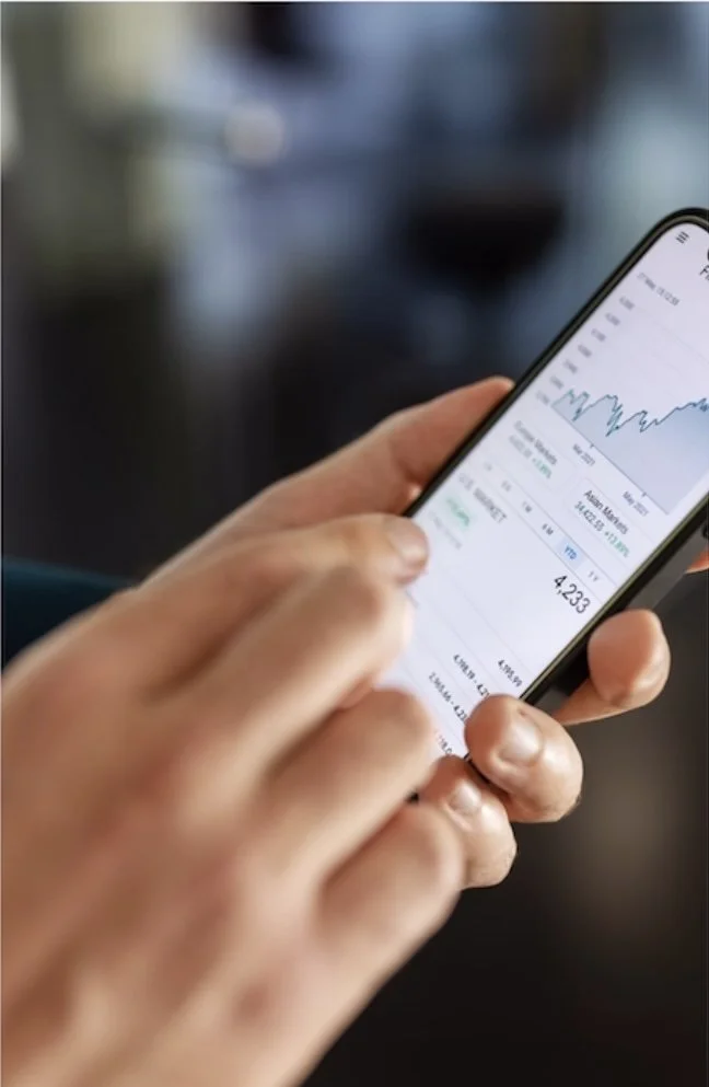 Person holding a smartphone displaying a stock market or financial chart.