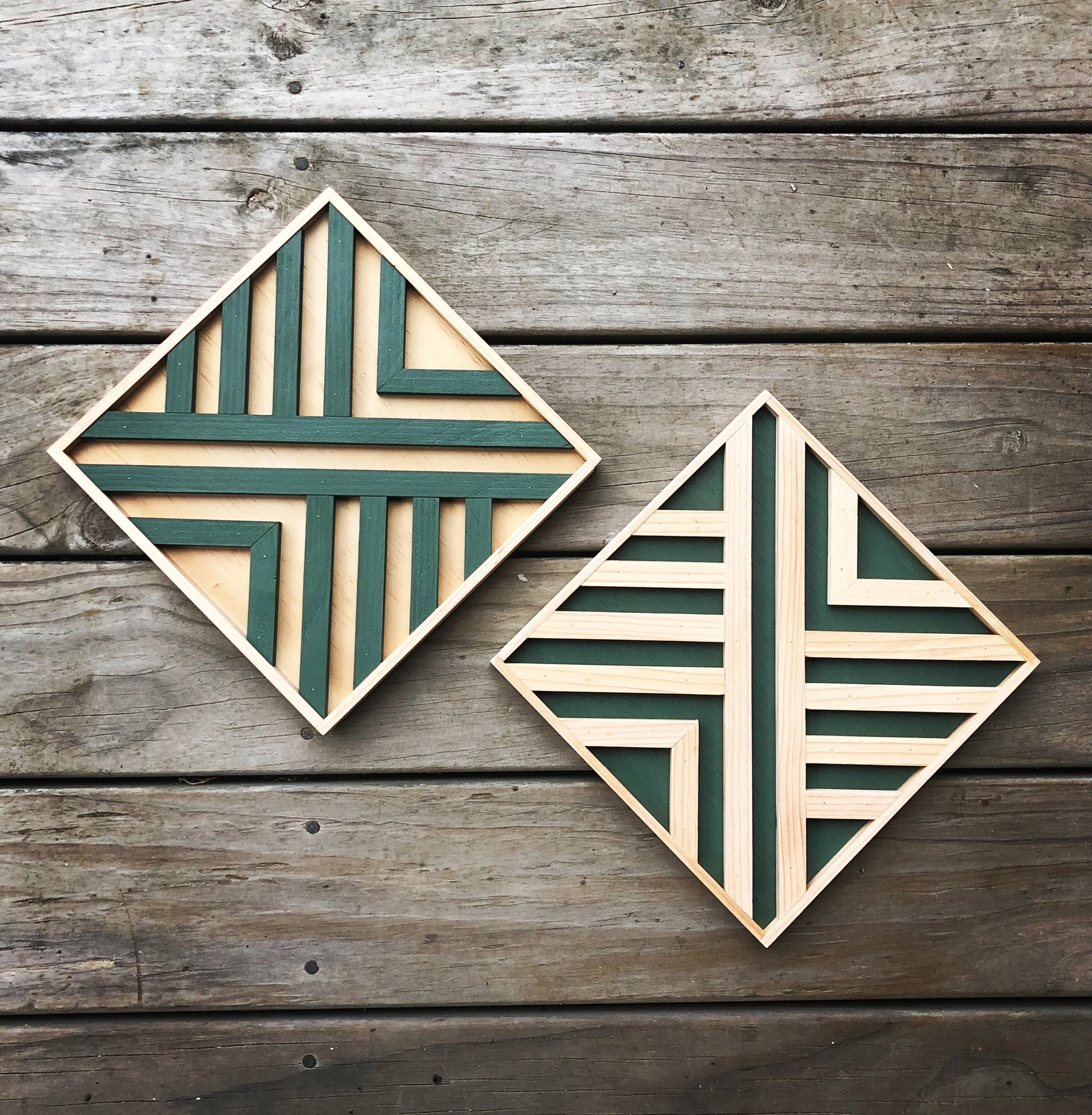 Geometric wooden art pieces with green and natural wood colors on a wooden floor