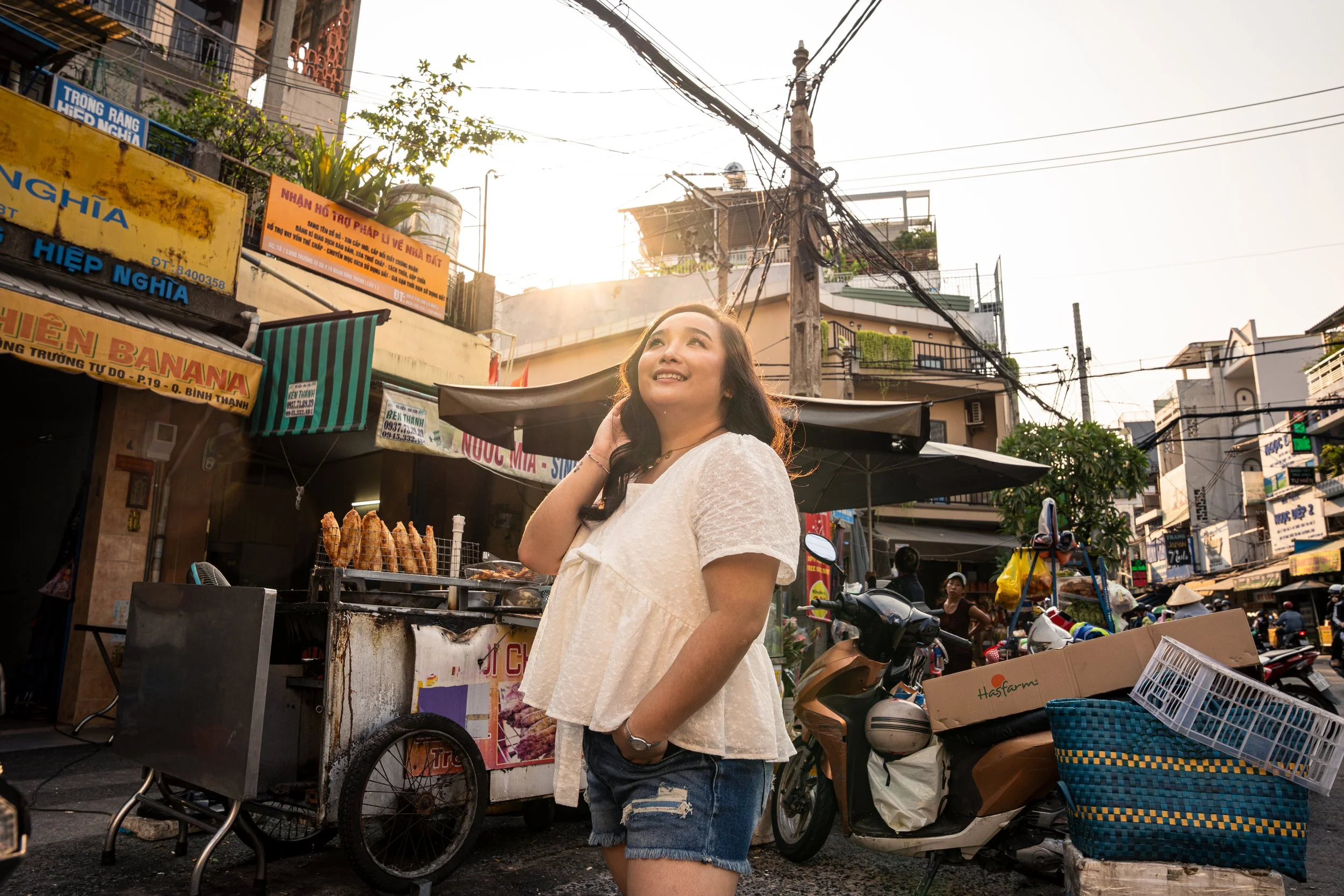 A woman looks up surrounded by baskets and street food in Ho Chi Minh City.